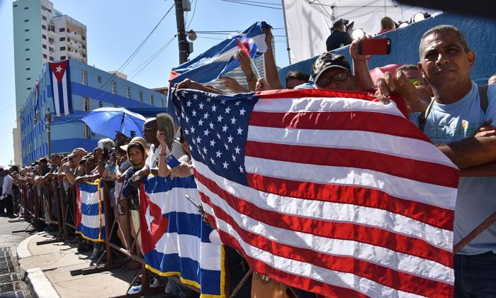 Des Cubains tiennent des drapeaux américain et cubain devant l'ambassade des États-Unis tandis que le drapeau américain est hissé au dessus du bâtiment, à La Havane. (Adalberto Roque/AFP/Getty Images)