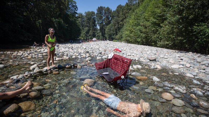 Un homme se rafraîchit dans l'eau glacée de la rivière Lynn Creek au nord de Vancouver, le 28 juin 2021. (The Canadian Press/Darryl Dyck) 