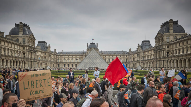 Des manifestants anti-vaccins passent devant le musée du Louvre alors que des milliers de personnes descendent dans les rues de la capitale française pour protester contre le nouveau passe sanitaire COVID-19 annoncé par le président de la République Emmanuel Macron, le 17 juillet 2021 à Paris, en France.(Kiran Ridley/Getty Images).