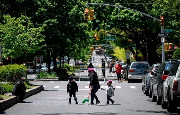 Une femme joue avec deux enfants dans une rue, le 13 mai 2020, dans l'arrondissement du Queens à New York. Image d'illustration (JOHANNES EISELE/AFP via Getty Images)