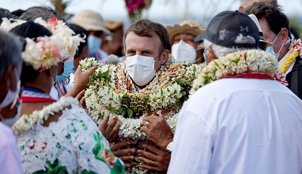 Le président Emmanuel Macron couvert de fleurs après son arrivée en Polynésie française, le 26 juillet 2021. (Photo par LUDOVIC MARIN/AFP via Getty Images)