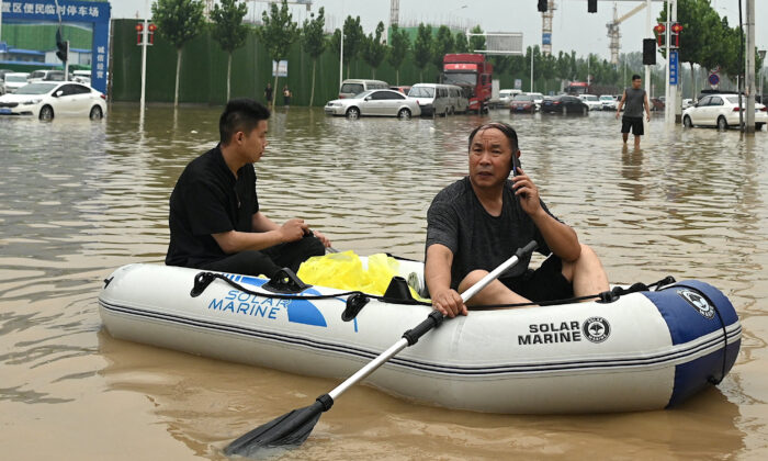 Des personnes utilisent un canot pneumatique pour traverser une rue inondée à la suite des inondations qui ont coûté la vie à au moins 33 personnes en début de semaine, dans la ville de Zhengzhou, dans la province chinoise du Henan, le 23 juillet 2021. (Noel Celis/AFP via Getty Images)