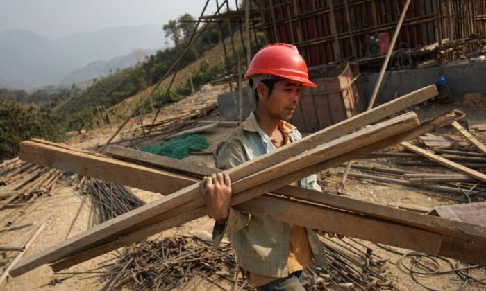 Un ouvrier chinois transporte des matériaux pour la première ligne ferroviaire reliant la Chine au Laos, un élément clé de l'Initiative ceinture et route (ICR ou nouvelle route de la soie) de Pékin à travers le Mékong, à Luang Prabang, au Laos, le 8 février 2020. (Aidan Jones/AFP via Getty Images)