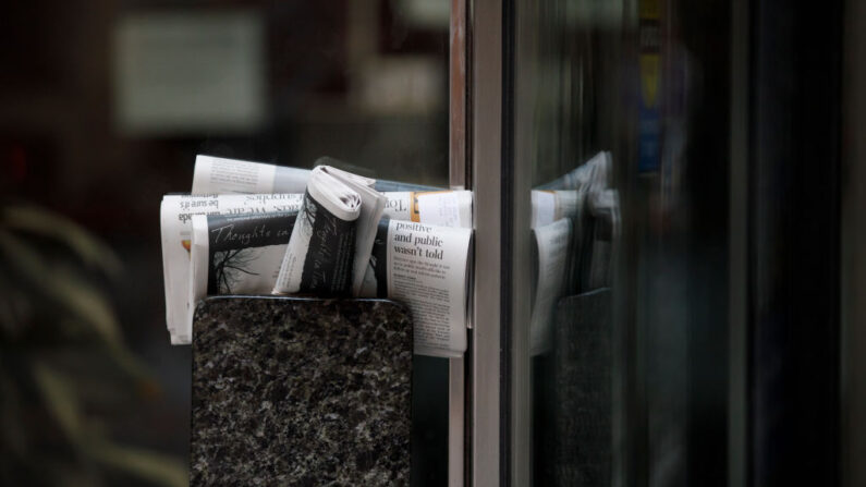 Des journaux sont entassés derrière une poignée de porte d'un bâtiment de Toronto, le matin du 1er avril 2020. (Cole Burston/Getty Images)