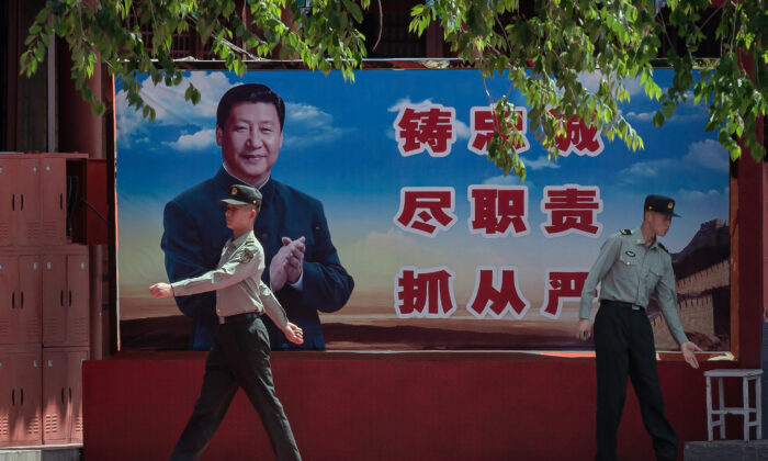 Des soldats passent devant une affiche du dirigeant chinois Xi Jinping près de l'entrée de la Cité interdite à Pékin, le 18 mai 2020. (Nicolas Asfouri/AFP via Getty Images) 