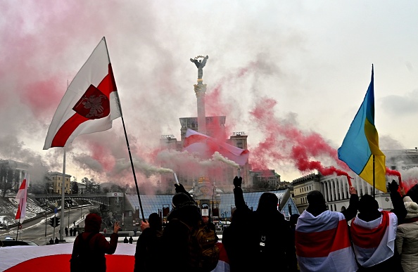 -Des membres de la diaspora biélorusse et des militants ukrainiens brandissent des fusées éclairantes blanches et rouges lors d'un rassemblement dans le centre de Kiev le 7 février 2021. Photo de Sergei SUPINSKY / AFP via Getty Images.