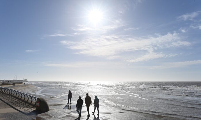 Des gens profitent du soleil en marchant le long de la plage de Blackpool, Lancashire, Royaume-Uni, le 16 mars 2021. (Paul Ellis/AFP via Getty Images)
