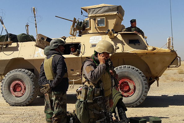 -Les forces de sécurité afghanes se tiennent près d'un véhicule blindé lors des combats en cours entre les forces de sécurité afghanes et les combattants talibans à la périphérie de Lashkar Gah, la capitale de la province d'Helmand, 2021. Photo de Sifatullah ZAHIDI / AFP via Getty Images.