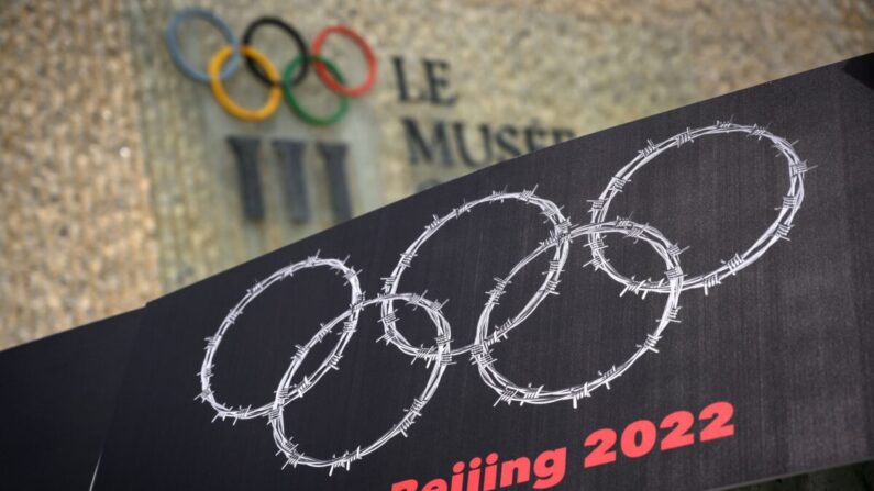 Une pancarte montrant des fils barbelés formant les anneaux olympiques à côté d’un panneau du musée des Jeux olympiques, lors d’une manifestation organisée par des militants tibétains et ouïghours contre les Jeux olympiques d’hiver de Pékin 2022, à Lausanne, en Suisse, le 23 juin 2021. (Fabrice Coffrini/AFP via Getty Images)