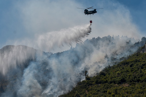 -Un hélicoptère Chinook largue de l'eau sur un incendie de forêt près de Malakasa, au nord d'Athènes, le 7 août 2021. Photo de Louisa GOULIAMAKI / AFP via Getty Images.