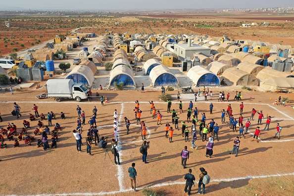 -De jeunes athlètes rassemblés dans un champ près d’un camp pour déplacés syriens lors des soi-disant "Camp Olympics 2020" dans le nord-ouest de la Syrie, le 7 août 2021. Photo d'OMAR HAJ KADOUR / AFP via Getty Images.