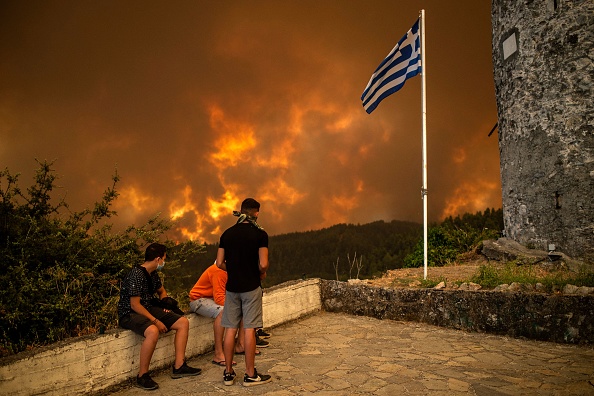 Les résidents locaux regardent l'incendie de forêt s'approchant du village de Gouves sur l'île d'Eubée la deuxième plus grande île grecque, le 8 août 2021. Photo par ANGELOS TZORTZINIS / AFP via Getty Images.