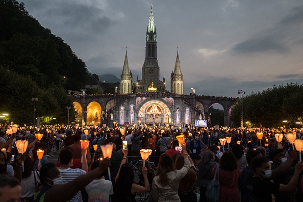 -Des pèlerins participent à la procession mariale aux flambeaux à Lourdes le 14 août 2021 pour célébrer l'Assomption de la Vierge Marie. Photo de Fred SCHEIBER / AFP via Getty Images.