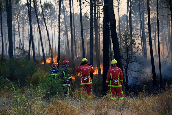 Des pompiers se rassemblent alors qu'ils travaillent sur un feu de forêt, à Vidauban dans le département du Var, dans le sud de la France, le 18 août 2021. (NICOLAS TUCAT/AFP via Getty Images)