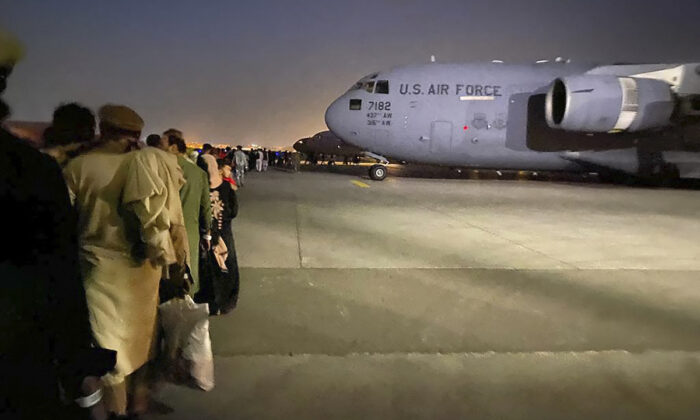 Après la prise de contrôle de Kaboul par les talibans, des Afghans font la queue pour monter à bord d'un avion militaire américain et quitter l'Afghanistan à l'aéroport militaire de Kaboul, le 19 août 2021. (Shakib Rahmani/AFP via Getty Images)