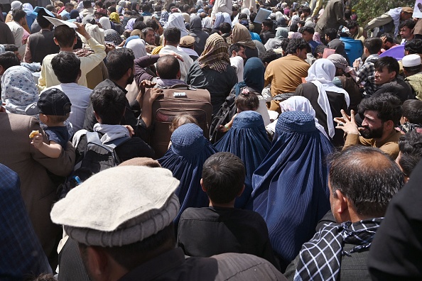 -Des Afghans se rassemblent au bord de la route près de la partie militaire de l'aéroport de Kaboul le 20 août 2021, dans l'espoir de fuir le pays. Photo de Wakil KOHSAR / AFP via Getty Images.