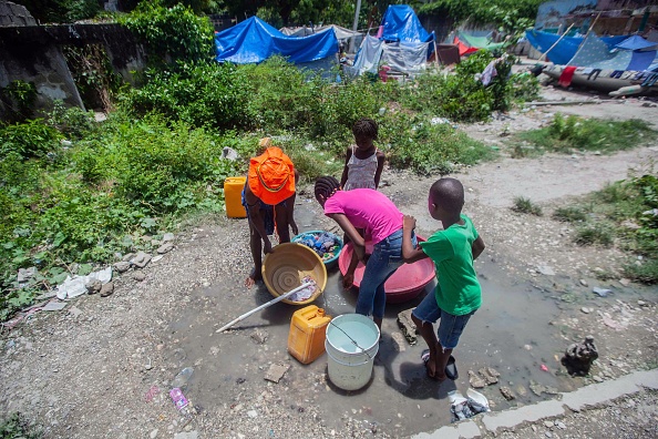 -Des enfants lavent des vêtements dans un camp pour les personnes qui ont perdu leur maison lors du tremblement de terre du 14 août aux Cayes, Haïti, le 23 août 2021. Photo de Richard Pierrin / AFP via Getty Images.