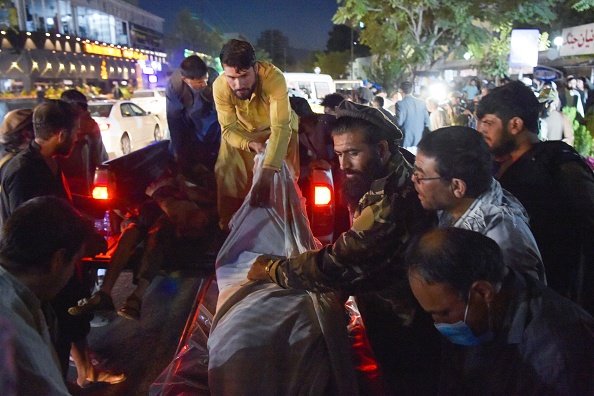 Des bénévoles et du personnel médical déchargent des corps d'une camionnette à l'extérieur d'un hôpital après deux puissantes explosions, qui ont tué 85 personnes, devant l'aéroport de Kaboul, le 26 août 2021.  (Photo : WAKIL KOHSAR/AFP via Getty Images)