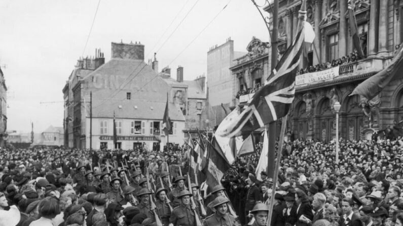 Des troupes britanniques défilent dans Cherbourg avec les drapeaux britannique et français, pour célébrer le Bastille Day et la récente libération de la ville des Allemands, le 14 juillet 1944. (Crédit photo FPG/Hulton Archive/Getty Images)