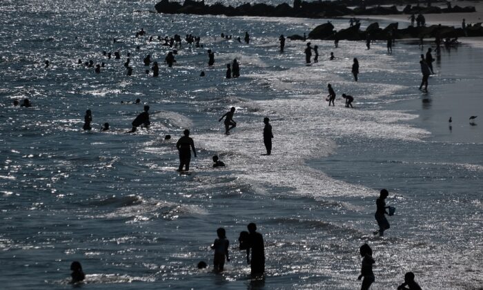 Des personnes se rafraîchissent sur la plage de Coney Island à Brooklyn, à New York, le 28 juin 2021, alors qu'un avis de chaleur est en vigueur. (Spencer Platt/Getty Images)