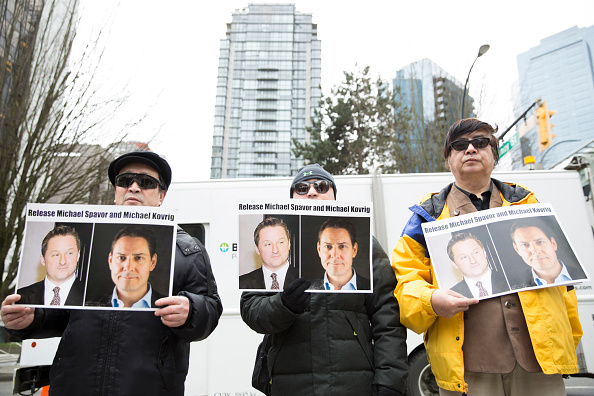 Manifestants avec les photos des Canadiens Michael Spavor et Michael Kovrig qui ont été arbitrairement détenus par la Chine, à Vancouver, le 6 mars 2019. (Photo par Jason Redmond / AFP via Getty Images)
