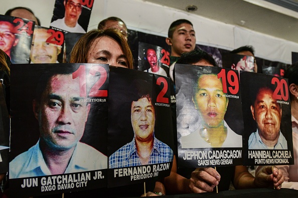 -Des proches et des sympathisants des victimes du massacre de Maguindanao en 2009 tiennent des photos des victimes lors d'une conférence de presse après le verdict dans l'affaire à Taguig, Manille, le 19 décembre 2019. Photo de Maria TAN / AFP via Getty Images.