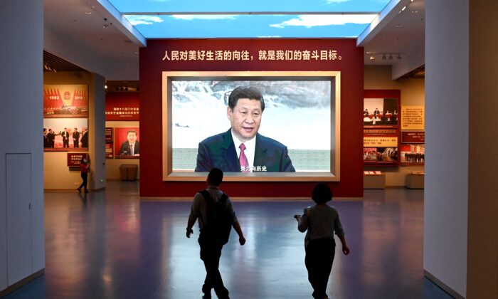 Des journalistes passent devant un écran montrant des images vidéo du dirigeant chinois Xi Jinping, lors d'une visite au Musée du Parti communiste chinois, près du stade national du Nid d'oiseau, à Pékin, le 25 juin 2021. (Noel Celis/AFP via Getty Images)