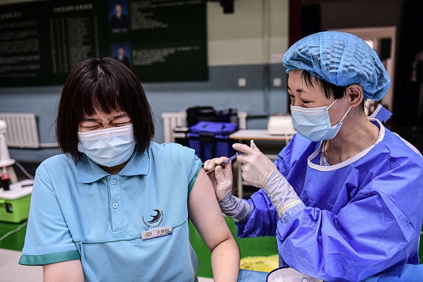 Une élève  réagit alors qu'elle reçoit le vaccin contre le Covid-19 de Sinopharm dans un lycée de Shenyang, dans la province chinoise du Liaoning (nord-est), le 28 juillet 2021. - (Photo by STR / AFP) / China OUT (Photo by STR/AFP via Getty Images)