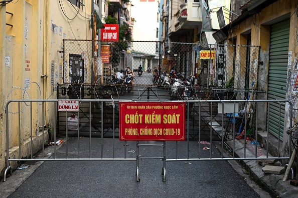 -Une barricade improvisée installée pour restreindre les déplacements des résidents à Hanoï, pour arrêter la propagation du virus du PCC. Photo de Manan VATSYAYANA / AFP via Getty Images.