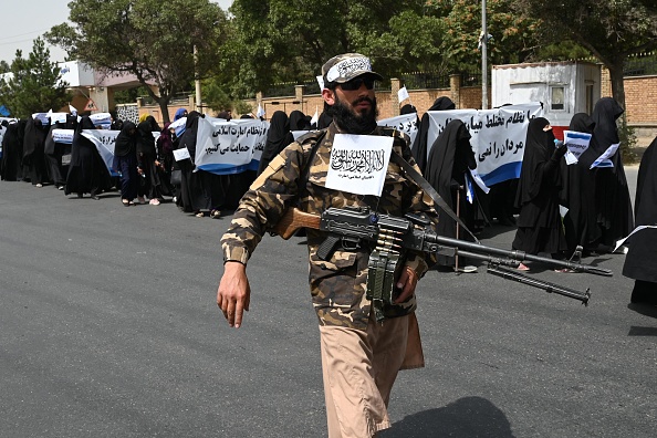 -Un combattant taliban armé escorte des femmes voilées alors qu'elles défilent lors d'un rassemblement pro-taliban devant l'Université d'éducation Shaheed Rabbani à Kaboul le 11 septembre 2021. Photo par Aamir QURESHI / AFP via Getty Images.