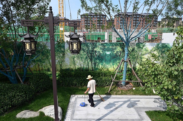 -Un ouvrier nettoie une zone d'exposition à côté du chantier de construction d'un complexe de logements Evergrande à Pékin le 13 septembre 2021.  Photo de GREG BAKER / AFP via Getty Images.