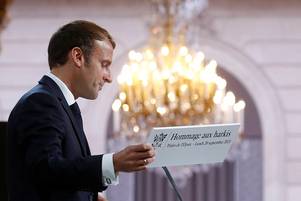 Le Président  Emmanuel Macron tient la pancarte "Hommage aux Harkis"  lors d'une cérémonie à la mémoire des Harkis, au palais de l'Élysée à Paris, le 20 septembre 2021. (Photo : GONZALO FUENTES/POOL/AFP via Getty Images)