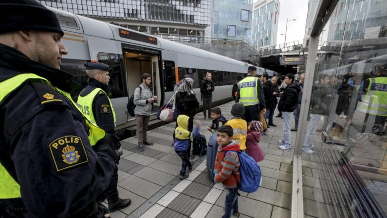 Des policiers et un groupe de migrants se tiennent sur la plate-forme à l'extrémité suédoise du pont entre la Suède et le Danemark à Malmo, en Suède, le 12 novembre 2015. (Stig-Ake Jonsson/AFP/Getty Images)