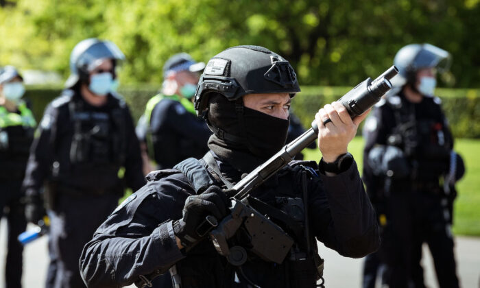 Un agent de la police anti-émeute brandit une arme en regardant les manifestants près du sanctuaire du souvenir, à Melbourne, en Australie, le 22 septembre 2021. (Darrian Traynor/Getty Images)