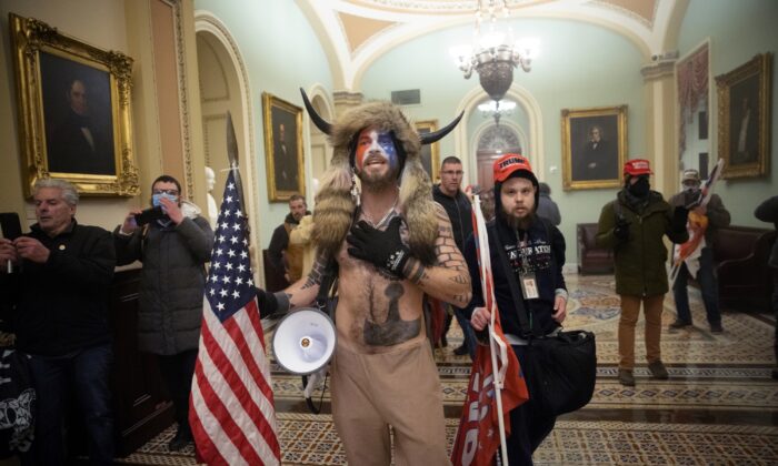 Le manifestant accusé d'être entré illégalement dans le Capitole américain surnommé le « chaman QAnon », Jacob Chansley (au centre), et d'autres manifestants devant la chambre du Sénat du Capitole américain à Washington, le 6 janvier 2021 (Win McNamee/Getty Images)