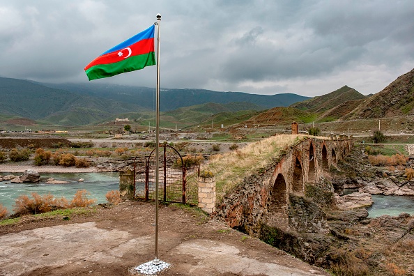 Un drapeau national azerbaïdjanais flotte à côté du pont médiéval de Khudaferin à la frontière du pays avec l'Iran, le 9 décembre 2020. Photo par STRINGER/AFP via Getty Images.