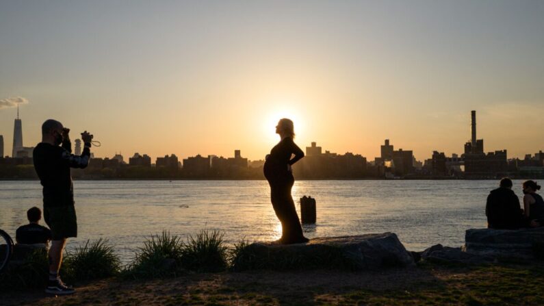 Une femme enceinte pose devant l'horizon de Manhattan au coucher du soleil,, N.Y., le 20 avril 2021. (Ed Jones/AFP via Getty Images)