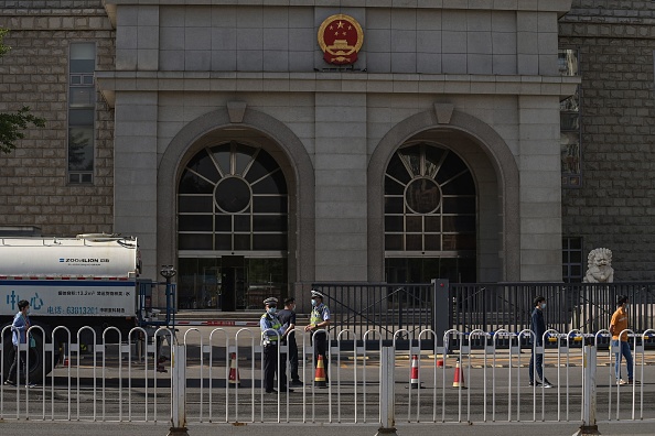 -Illustration- Des policiers se tiennent devant le deuxième tribunal populaire intermédiaire de Pékin le 27 mai 2021. Photo de NICOLAS ASFOURI /AFP via Getty Images.
