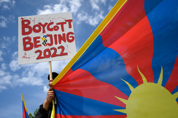 Un activiste tibétain tient une pancarte et un drapeau tibétain lors d'une manifestation contre les Jeux olympiques d'hiver de Pékin 2022 devant le Musée Olympique à Lausanne, le 23 juin 2021. (Photo : FABRICE COFFRINI/AFP via Getty Images)
