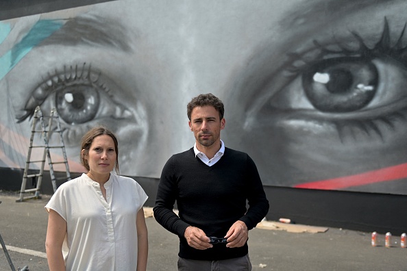 Sibylle et Damien, frère et sœur de la disparue Tiphaine Véron au Japon, posent devant une peinture murale de l'artiste de rue français Rebeb près de la gare de Poitiers représentant les yeux de Tiphaine. (Photo : GUILLAUME SOUVANT/AFP via Getty Images)