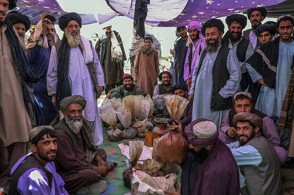 -Des hommes se rassemblent autour de sacs contenant de l'héroïne et du haschich alors qu'ils négocient et vérifient la qualité sur un marché de la drogue à la périphérie de Kandahar le 24 septembre 2021. Photo de Bulent KILIC/AFP via Getty Images.