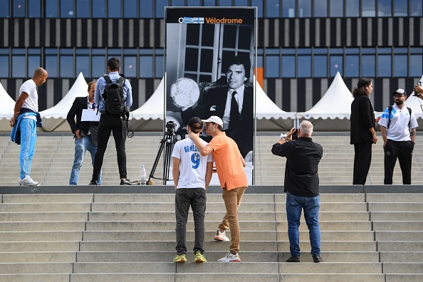 -Des supporters prennent en photo le portrait de Bernard Tapie, ancien propriétaire du club de football français de l'Olympique de Marseille, affiché devant le stade Vélodrome de Marseille le 3 octobre 2021, après l'annonce de son décès à l'âge de 78. Photo CLEMENT MAHOUDEAU / AFP via Getty Images.