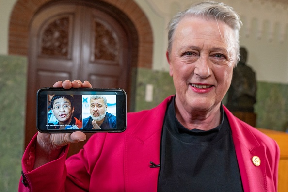 La présidente du comité du prix Nobel de la paix, présente sur un téléphone portable les photos des journalistes Maria Ressa et Dmitry Muratov pour annoncer les lauréats du prix Nobel de la paix 2021 à Oslo, le 8 octobre 2021. Photo par Heiko Junge / NTB / AFP via Getty Images.