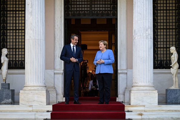-Le Premier ministre grec Kyriakos Mitsotakis salue la chancelière allemande Angela Merkel lors de sa visite à Athènes le 29 octobre 2021. Photo par ARIS MESSINIS / AFP via Getty Images.