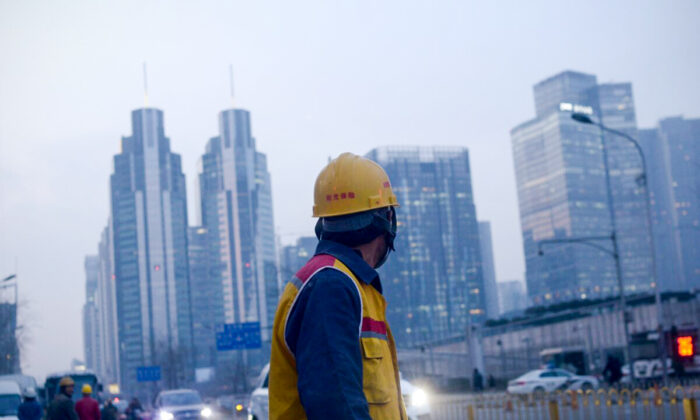 Un ouvrier chinois observe la ville en marchant dans une rue après le travail à Pékin, le 28 décembre 2015. (WANG ZHAO/AFP via Getty Images)