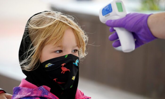 Un enfant porte un masque alors qu'on vérifie sa température à l'entrée d'Alton Towers à Alton, en Angleterre, le 4 juillet 2020. (Christopher Furlong/Getty Images)