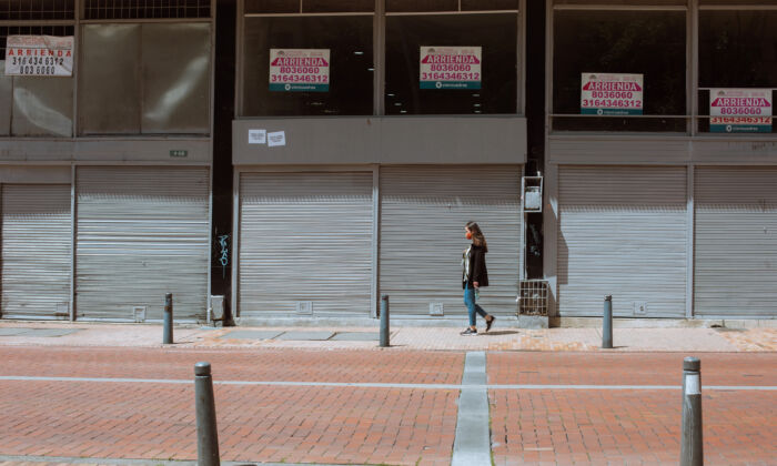 Une jeune fille passe devant les locaux vides d'entreprises affichant des panneaux de location à Bogota, Colombie, le 15 octobre 2021. (Alejandro Gomez/The Epoch Times)