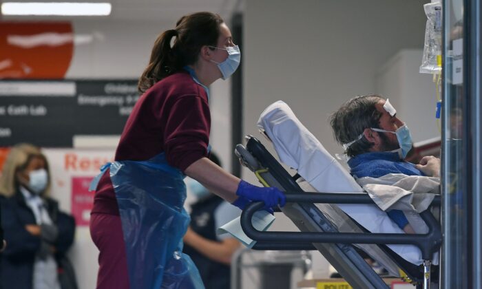 Une infirmière pousse un patient, portant un masque facial, alors qu'il est allongé sur un lit, à l'intérieur de l'hôpital St Thomas, dans le nord de Londres, le 1er avril 2020 (Daniel Leal-Olivas/AFP via Getty Images)