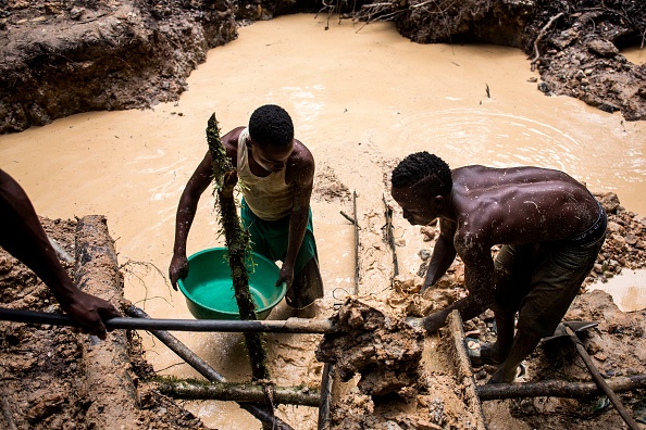 Des mineurs artisanaux congolais utilise de l'eau pour séparer le sol du minerai, sur le site d'extraction d'or de Mabukulu le 11 juillet 2018 dans la province de l'Ituri. Photo de John WESSELS / AFP via Getty Images.