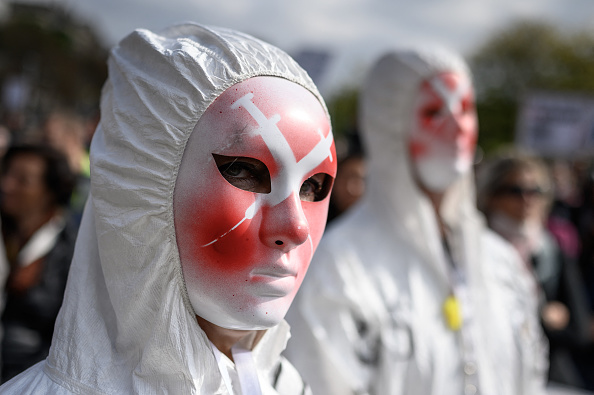 Un manifestant porte un masque représentant des seringues lors d'un rassemblement contre les mesures contre les coronavirus, le passeport sanitaire Covid-19 et la vaccination à Genève le 9 octobre 2021. (Photo : FABRICE COFFRINI/AFP via Getty Images)